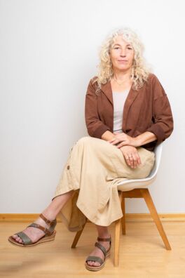 Petra Endres von Dialogwege sitzt auf einem Stuhl.